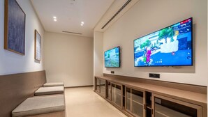 A hallway with two flat-screen TVs mounted on the wall, a bench, and a wooden cabinet with glass doors. - Luxurious 1bedroom All Bills Included (Dubai)