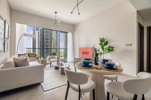 Uma sala de estar moderna com um sofá, cadeiras, uma mesa de jantar com pratos azuis e um letreiro 'GUEST READY'.