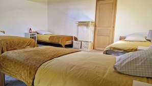 Una habitación con tres camas, una puerta de madera y un armario blanco.
