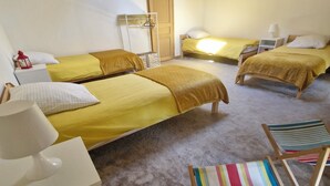 Una habitación con dos camas, una silla blanca, una silla de playa a rayas y una puerta de madera.