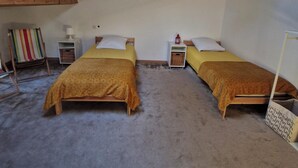 Una habitación con dos camas, un tragaluz, una mesita pequeña y una toalla a rayas de colores.