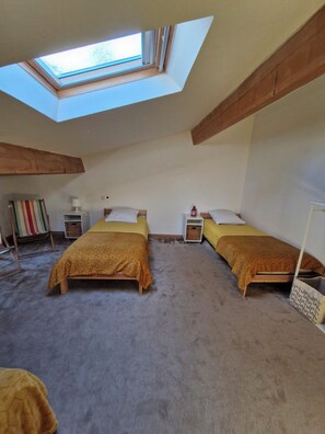 Ein Zimmer mit zwei Betten, einem Oberlicht, einem kleinen Tisch und einem bunten, gestreiften Handtuch.