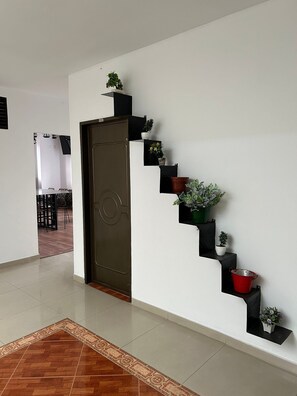 A modern interior with a dark wooden door, a staircase with potted plants, and a patterned rug. - Hotel Coliving Puerto Living (Barrancabermeja)