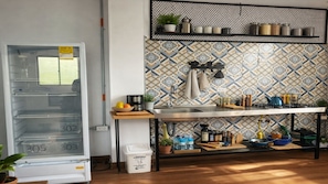 A kitchen with a tiled backsplash, a stainless steel sink, and a variety of kitchen items on the counter.