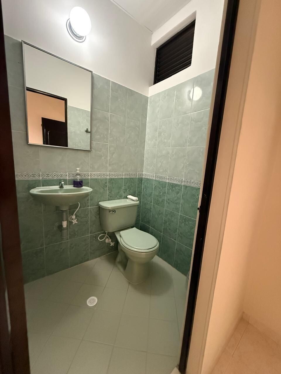 A bathroom with a toilet, sink, and mirror.