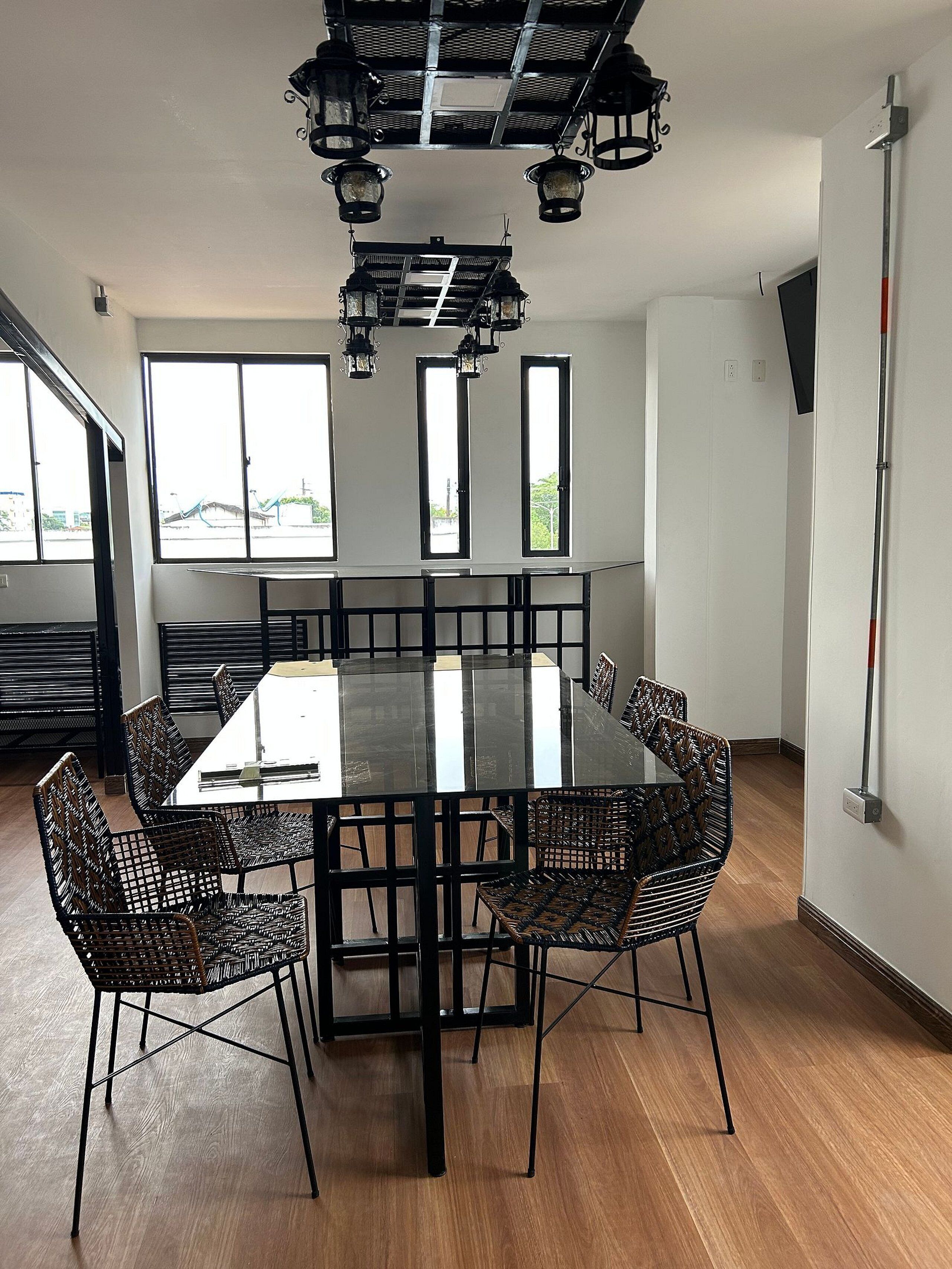 A modern dining area with a rectangular table, six chairs, and a ceiling with hanging lights.