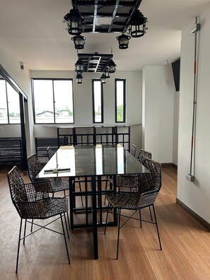 A modern dining area with a rectangular table, six chairs, and a ceiling with hanging lights. - Hotel Coliving Puerto Living (Barrancabermeja)