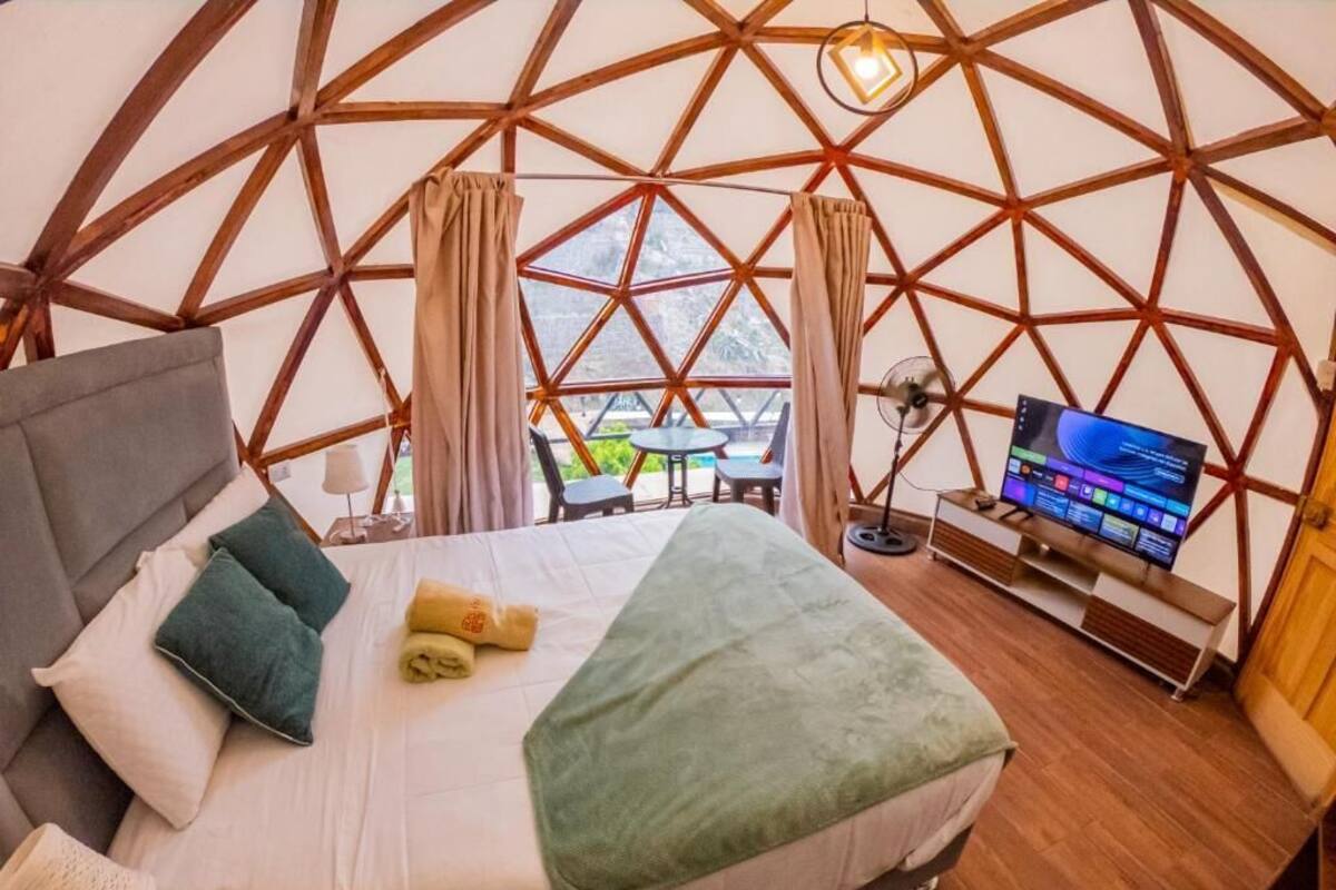 Een kamer met een bed, een televisie en uitzicht door een groot raam.