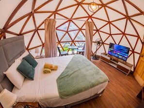 A room with a bed, a TV, and a view through a large window. - KAY PACHA WELLNESS PLACE (Andres Avelino Caceres Dorregaray)