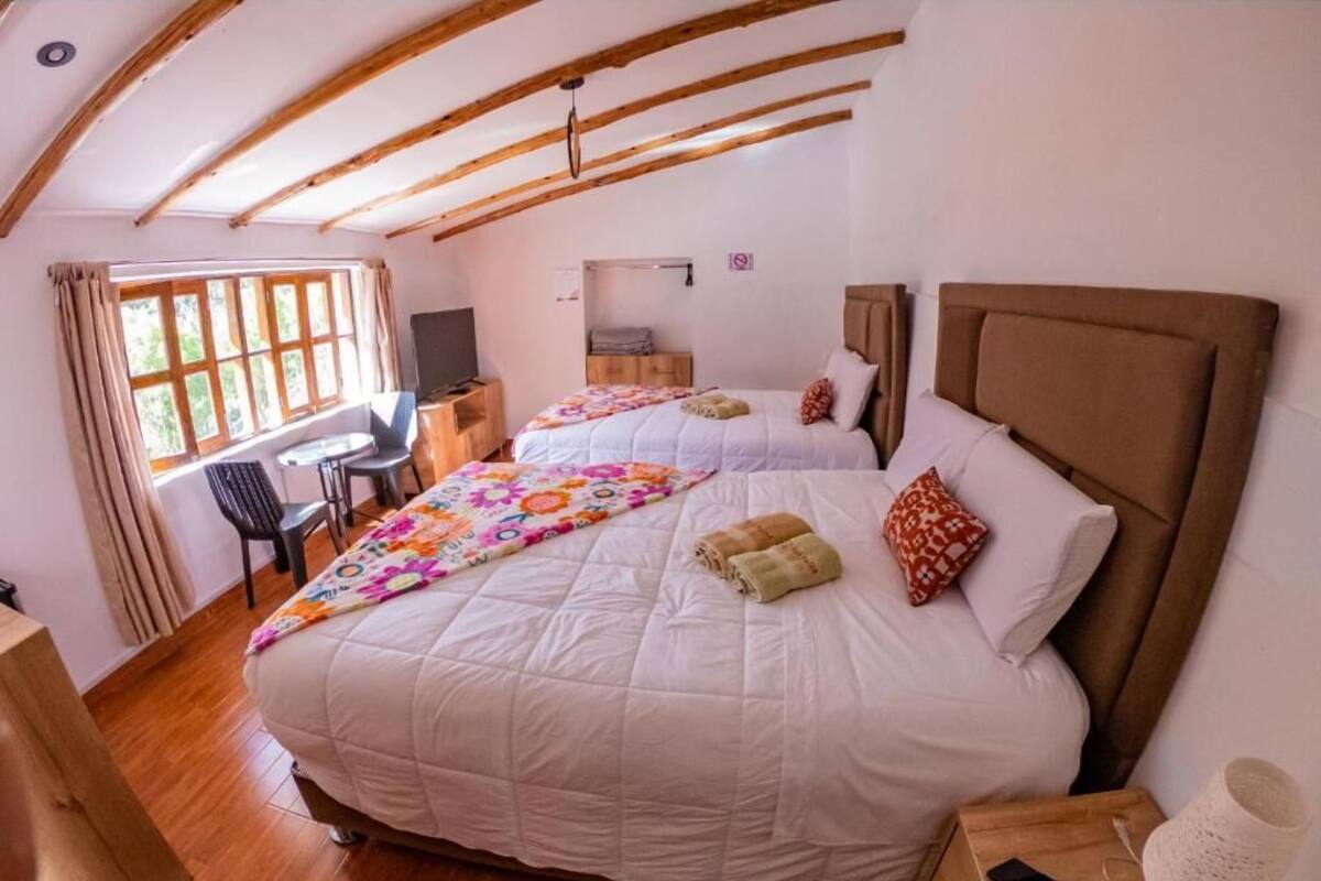 Een slaapkamer met twee bedden, een bureau, een stoel en een televisie.