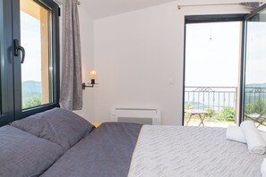 Ein Schlafzimmer mit Bett, Fenster, Balkon und Wandheizung.