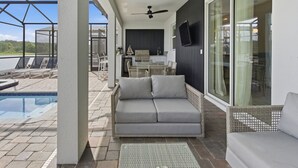 Un espace extérieur abrité comprenant une piscine, un canapé, une table à manger et un barbecue.