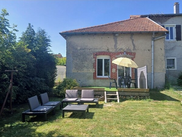 A house with a patio area featuring outdoor furniture and a yellow umbrella.