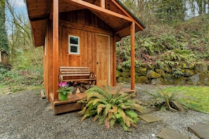 A wooden cabin with a porch, a bench, and a potted plant. - Fun Retreat! Playground, arcade, sauna, EV charger, 12mi SEA, 1mi to light rail (Kent)