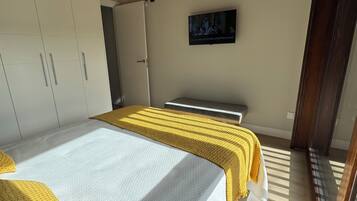 A bedroom with a bed, wardrobe, and a television on the wall.