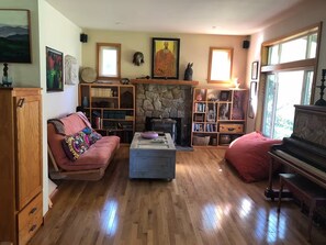 Un salon chaleureux avec une cheminée, des étagères à livres, un piano et un canapé.