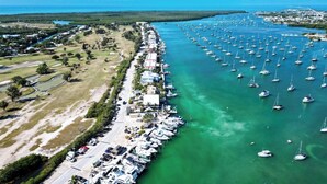 An aerial view of a marina with numerous boats docked along a waterfront, surrounded by residential buildings and open grassy areas. - Boot Key Harbor Oasis a 2-bedroom, 2-bath half duplex on Boot Key Harbor (Marathon)
