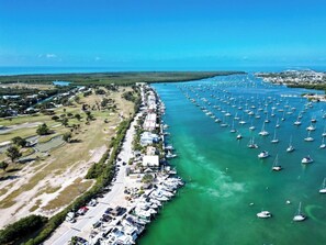 An aerial view of a marina with numerous boats docked along a waterfront, surrounded by residential buildings and open grassy areas. - Boot Key Harbor Oasis a 2-bedroom, 2-bath half duplex on Boot Key Harbor (Marathon)