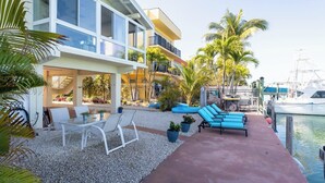 A waterfront property with a patio, lounge chairs, and a marina. - Boot Key Harbor Oasis a 2-bedroom, 2-bath half duplex on Boot Key Harbor (Marathon)