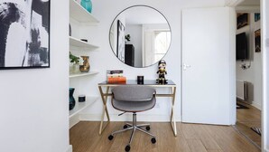 Huoneessa on työpöytä, tuoli, peili ja hyllyjä, joilla on koriste-esineitä.