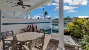 Ein überdachter Außenbereich mit Pool, Tisch und Stühlen sowie einem Deckenventilator.