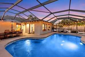 Une piscine couverte avec un espace patio, une table à manger et des chaises.