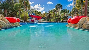 Ein Pool mit Wasserrutsche, umgeben von Palmen und Felsen.