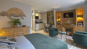 Une chambre à coucher comprenant un lit, un bureau, une chaise, une cheminée et un téléviseur.