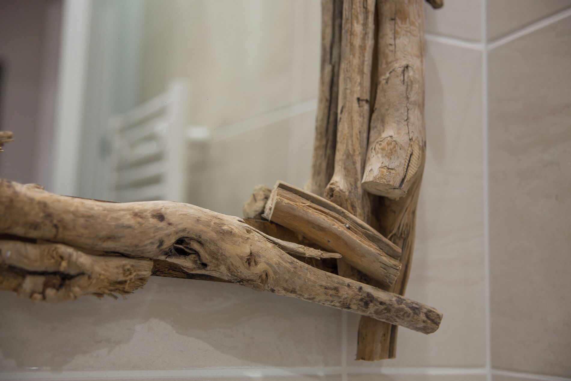 A bathroom with a white tiled wall and a wooden branch decoration.