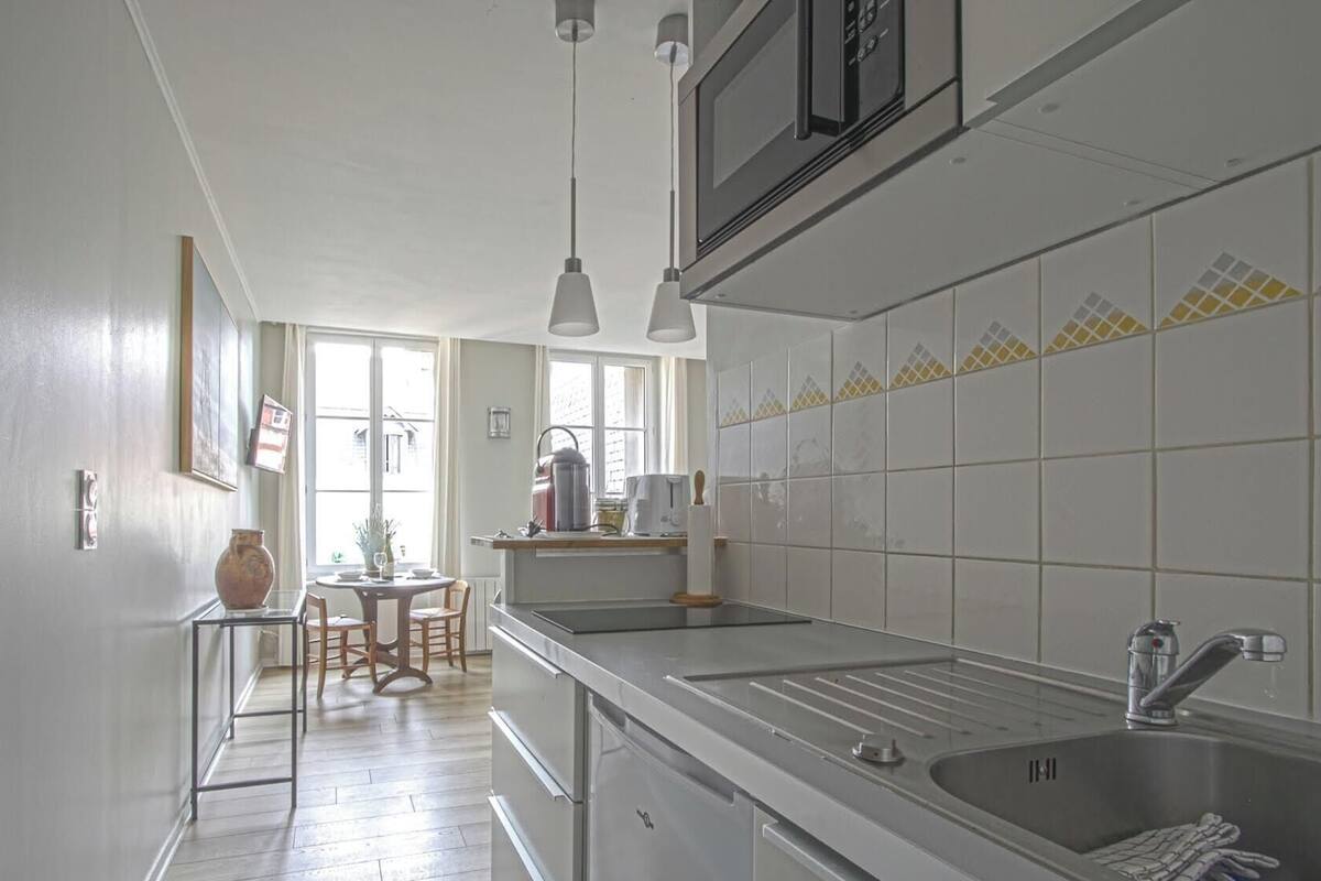 A kitchen with a sink, stove, and dining area with chairs and a table.