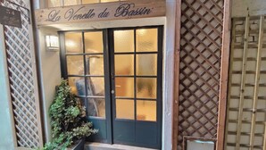 A building entrance with a sign reading 'La Venelle du Bassin,' a black door with frosted glass panels, and a lattice window to the right. - La Venelle du Bassin (Honfleur)