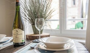 A bottle of Domaine de la Minotière Cidre Bouché wine, a glass, and a bowl on a table with a view of a building through a window.