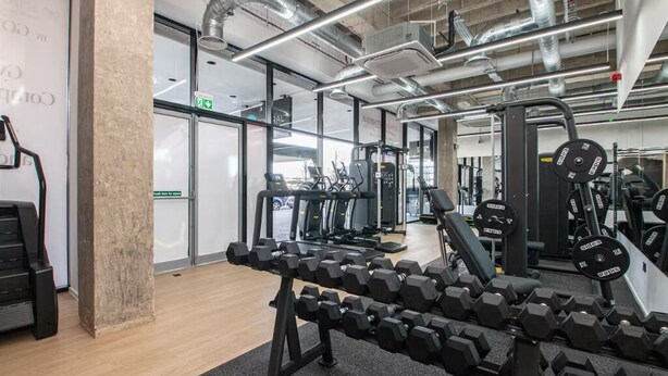 A gym with exercise equipment, a weight bench, and a treadmill. - Above MK Station, Modern Studio + Gym & Parking (Milton Keynes)