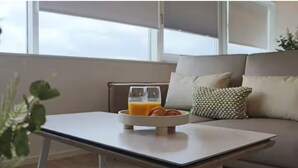 A modern living room with a sofa, a coffee table, and a window. - Above MK Station, Modern Studio + Gym & Parking (Milton Keynes)