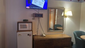 Une chambre d’hôtel équipée d’une télévision affichant une page web sur les prêts personnels, d’un four à micro-ondes, d’un réfrigérateur, d’une commode en bois, d’un miroir et d’une lampe.