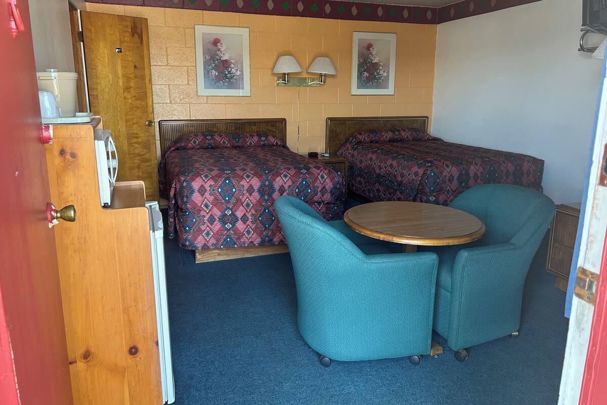 A room with two beds, a small round table, and two chairs.