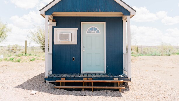 A small, single-story building with a light blue door and a white-framed window. - Farmside Tiny Home (Lyman)