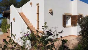 Un edificio bianco con una scala, una finestra con persiane di legno e un piccolo balcone.