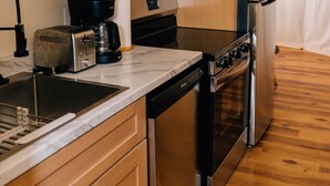 Eine kleine Küche mit Holzausstattung, einer Mikrowelle, einem Toaster, einer Kaffeemaschine und einem Kühlschrank.