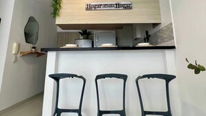 A kitchen area with a wooden countertop, a sign above the counter, and three chairs in front. - MARETA TORICES HOUSE (Cartagena de Indias)
