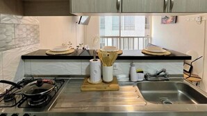 A kitchen with a gas stove, stainless steel sink, wooden cutting board, and kitchen utensils. - MARETA TORICES HOUSE (Cartagena de Indias)