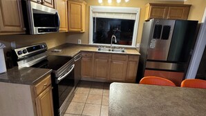 A kitchen with wooden cabinets, a stainless steel refrigerator, a microwave, an oven, and a sink. - Cozy 1-bedroom house with sofa sleeper, and air mattress in quaint Nashville (Nashville)