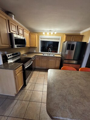 A kitchen with wooden cabinets, a stainless steel refrigerator, a microwave, an oven, and a sink. - Cozy 1-bedroom house with sofa sleeper, and air mattress in quaint Nashville (Nashville)