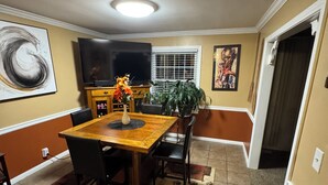A dining area with a wooden table, chairs, a TV, and artwork on the walls. - Cozy 1-bedroom house with sofa sleeper, and air mattress in quaint Nashville (Nashville)