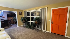 A carpeted hallway with a door, a window, and a desk with a chair. - Cozy 1-bedroom house with sofa sleeper, and air mattress in quaint Nashville (Nashville)