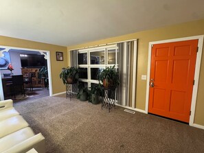 A carpeted hallway with a door, a window, and a desk with a chair. - Cozy 1-bedroom house with sofa sleeper, and air mattress in quaint Nashville (Nashville)