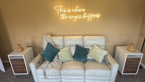 A white leather sofa with decorative pillows, two side tables with vases, and a neon sign on the wall. - Cozy 1-bedroom house with sofa sleeper, and air mattress in quaint Nashville (Nashville)