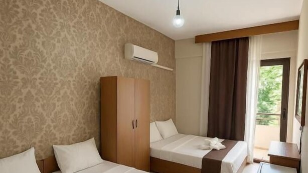 Ein Hotelzimmer mit zwei Betten, einem Kleiderschrank, einem Schreibtisch und einem Fenster mit Vorhängen.