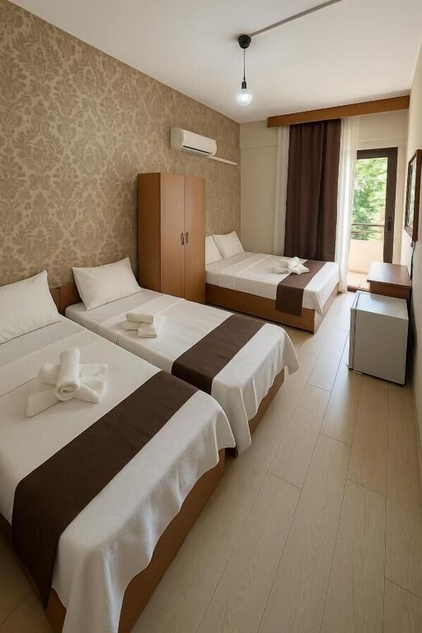 Habitación de hotel con dos camas, un armario, un escritorio y una ventana con cortinas.