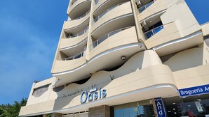 Een meerlaags hotel met een modern ontwerp, met een opvallend 'Oasis' bord, een begane grond ingang en een zichtbare etalage.